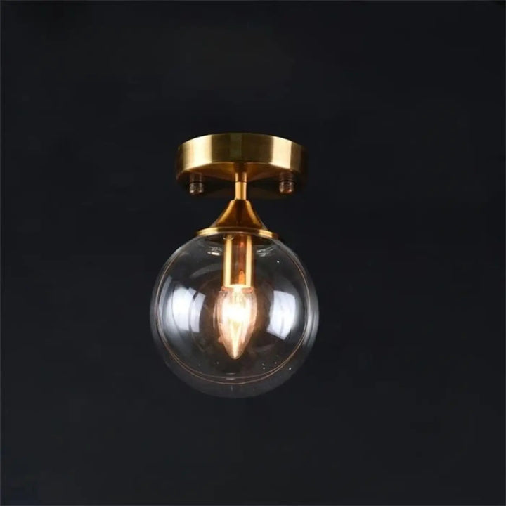 Luminaire plafonnier orbane avec anneau doré et boule lumineuse en verre clair et finition laiton chic plafond