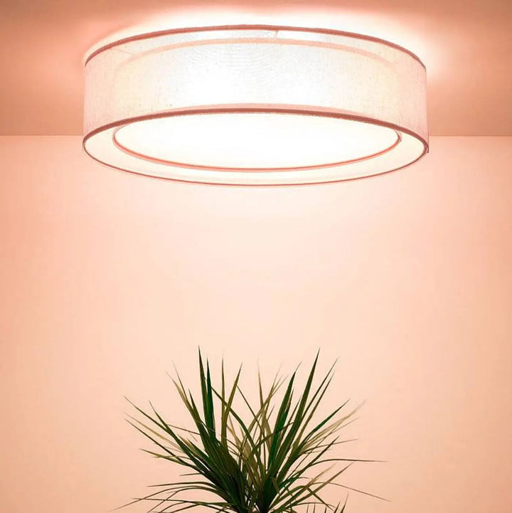 Luminaire plafonnier rond rose clair avec abat-jour en tissu blanc doux et bordure métallique subtile pu ro