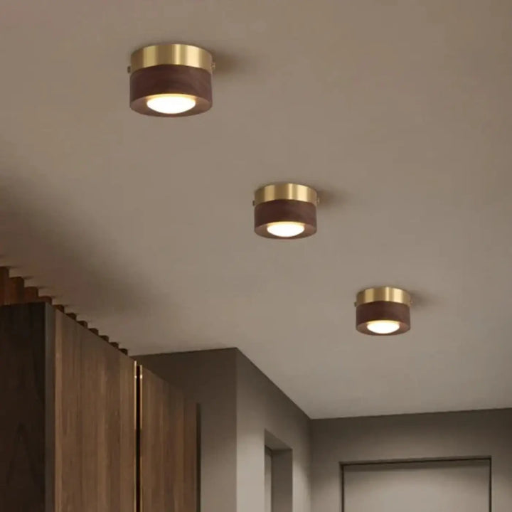 Luminaire plafonnier ulori à trois spots encastrés avec finition laiton doré et accents bois naturel diffusant une lumière chaude