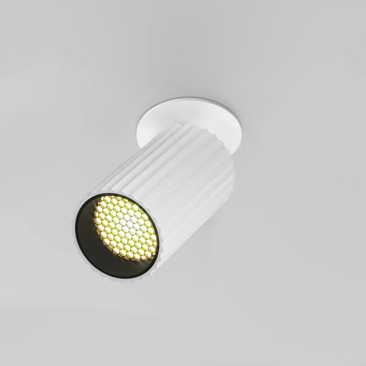 Spot semi-encastré calipso cylindre cannelé blanc avec led hexagonales et bord intérieur noir émettant une lueur chaude