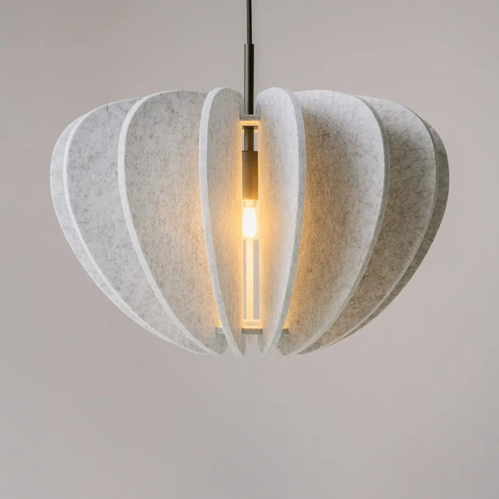 Suspension luminaire cambio avec matériaux feutrés off-white en pétales superposés au-dessus d’une table élégante