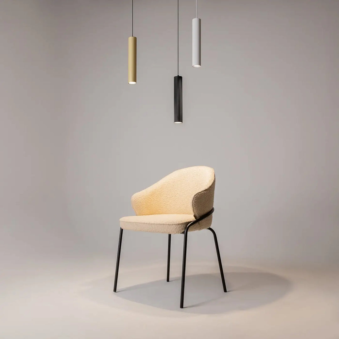Chaise rembourrée couleur crème avec pieds et cadre en métal noir au-dessus d’un espace d’une table suspension artisan
