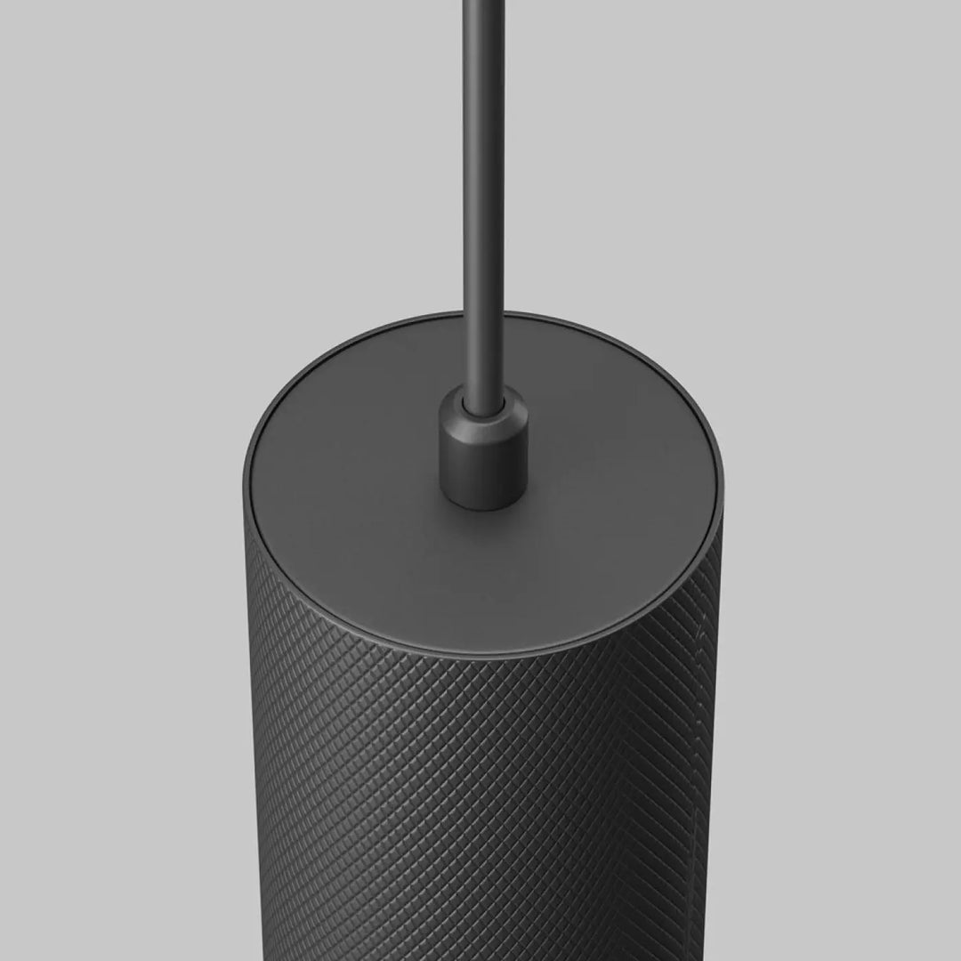 Suspension artisan noire cylindrique en surface texturée en losanges avec finition mate au-dessus d’une table