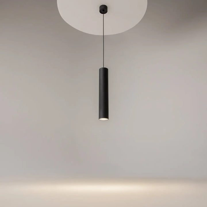 Suspension luminaire artisan noire cylindrique au-dessus d’une table avec finition mate et fixation de plafond circulaire