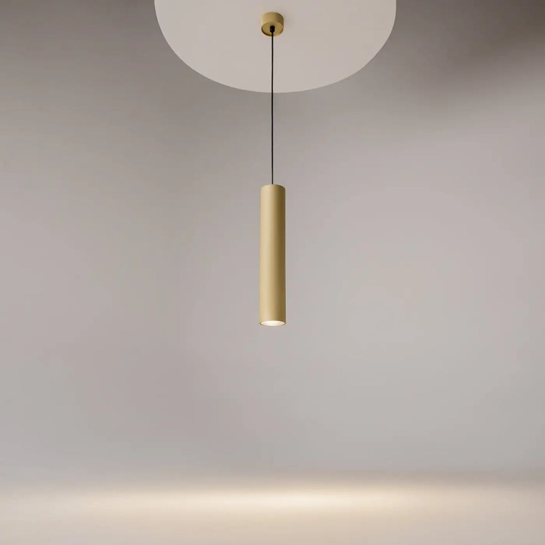 Suspension artisan cylindrique au-dessus d’une table avec finition mate dorée et design minimaliste