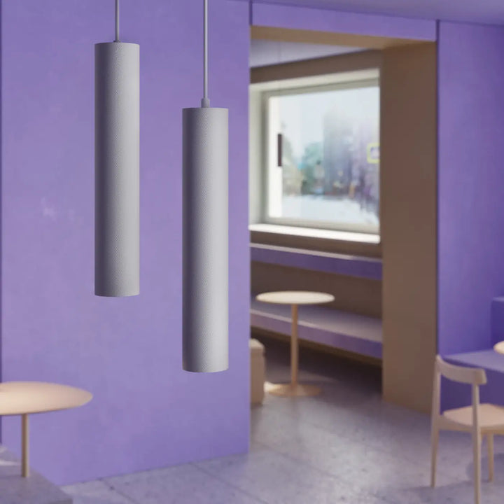 Deux suspensions artisan en forme cylindrique avec finition mate grise suspendues au-dessus d’une table