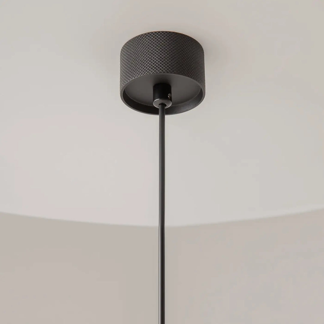 Suspension artisan noire avec finition mate et design cylindrique au-dessus d’une table pour un éclairage élégant
