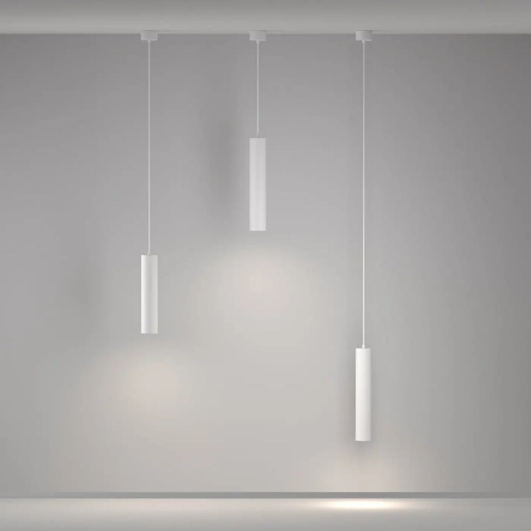 Suspension artisan en cylindre blanc minimaliste suspendue à différentes hauteurs au-dessus d’une table avec lumière douce