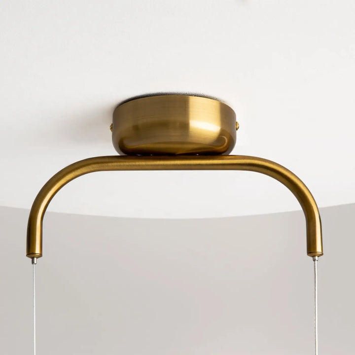 Suspension cabaret en laiton courbé poli avec verre transparent suspendue au-dessus d’une table moderne