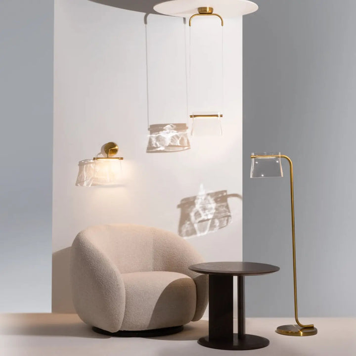 Beige fauteuil en tissu doux et texturé avec contours arrondis parfait pour suspension cabaret en verre transparent au-dessus d’une table