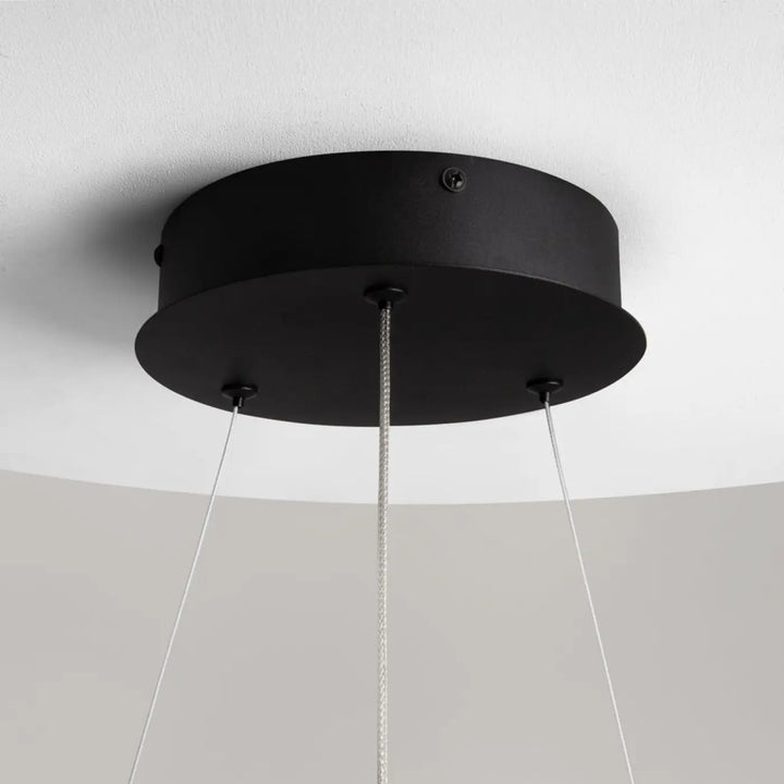 Suspension curve anneau ondulé en aluminium noir avec fixation plafond circulaire et trois câbles fins descendent