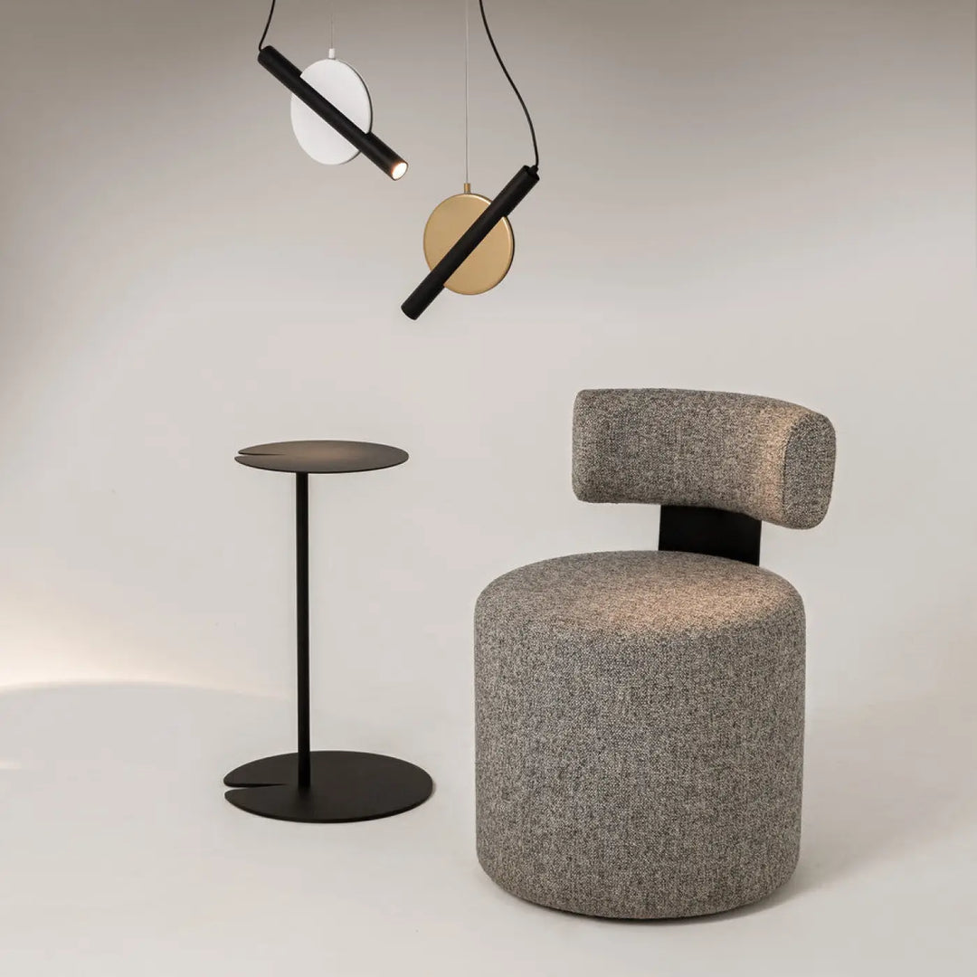 Suspension enigma led avec orientation réglable associée à un fauteuil gris en tissu à structure métallique noire