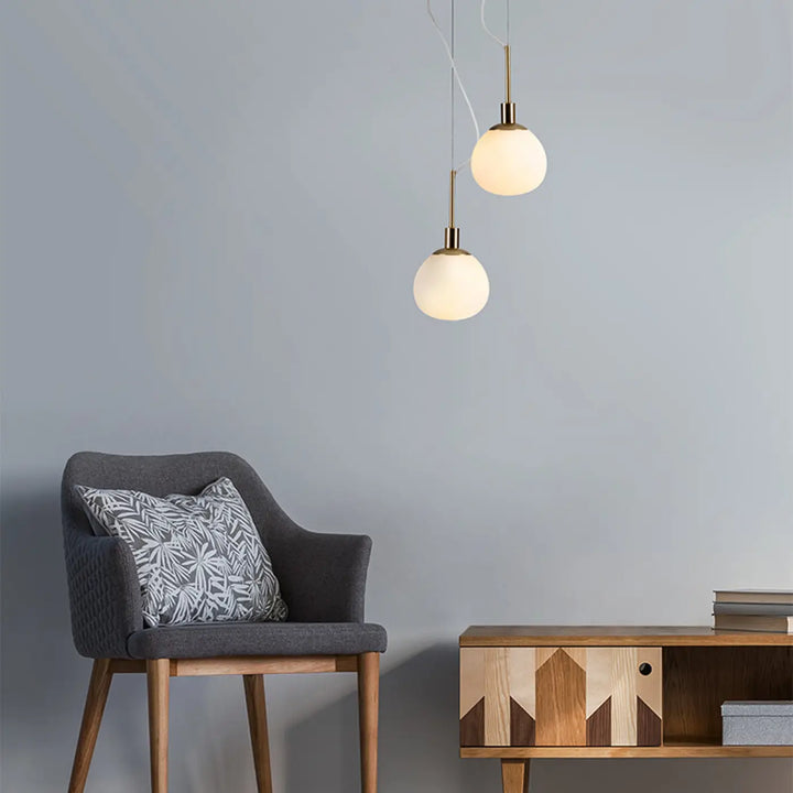 Deux suspensions luminaire erich avec globe en verre soufflé et finition laiton dans un style art déco pour lumière douce