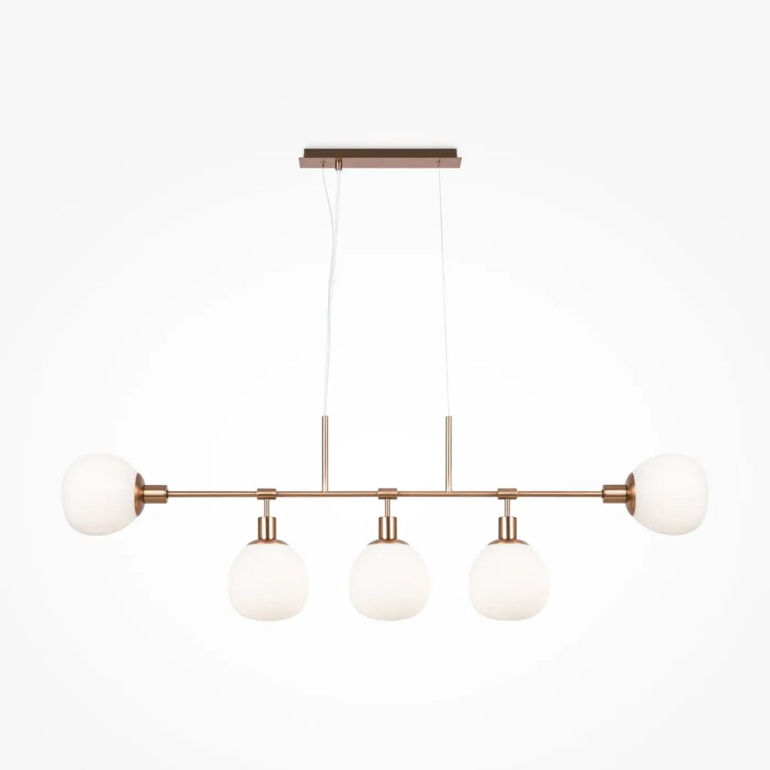 Suspension luminaire erich linéaire en cuivre moderne avec quatre globes en verre givré au-dessus d’une table