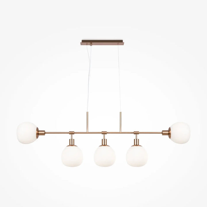 Suspension luminaire erich linéaire en cuivre moderne avec quatre globes en verre givré au-dessus d’une table