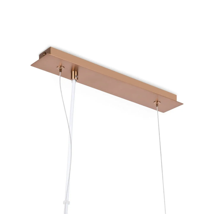 Suspension luminaire erich linéaire en pendentif rectangulaire en rose gold au-dessus d’une table avec cinq globes blanc