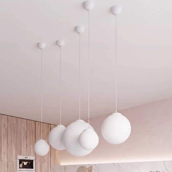 Suspension Ugo à globe en verre blanc et monture blanche dans un intérieur contemporain