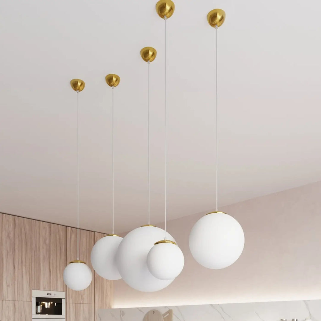 Suspension Ugo à globe en verre blanc et monture dorée dans un intérieur contemporain