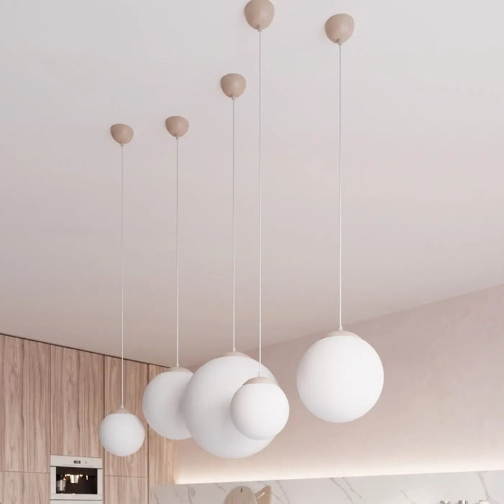 Suspension Ugo à globe en verre blanc et monture taupe dans un intérieur contemporain