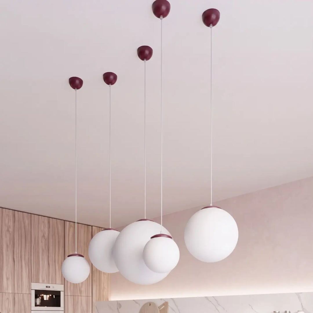 Suspension Ugo à globe en verre blanc et monture bordeaux dans un intérieur contemporain