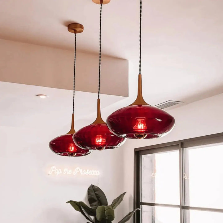 Suspension luminaire modèle grace avec trois abat-jours en verre soufflé rouge et tiges en bois chaleureux