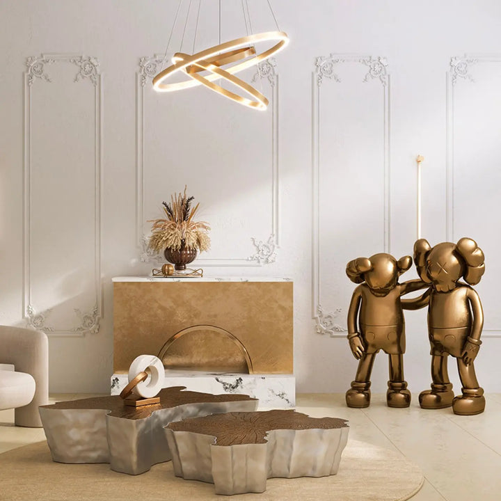 Deux figurines dorées style kaws avec surface métallique polie reflétant la lumière pour suspension led rim rim