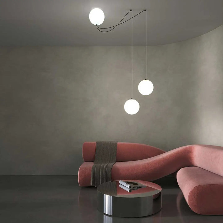 Suspension luminaire twins avec trois globes en verre blanc suspendus par cordons noirs au-dessus d’une table led