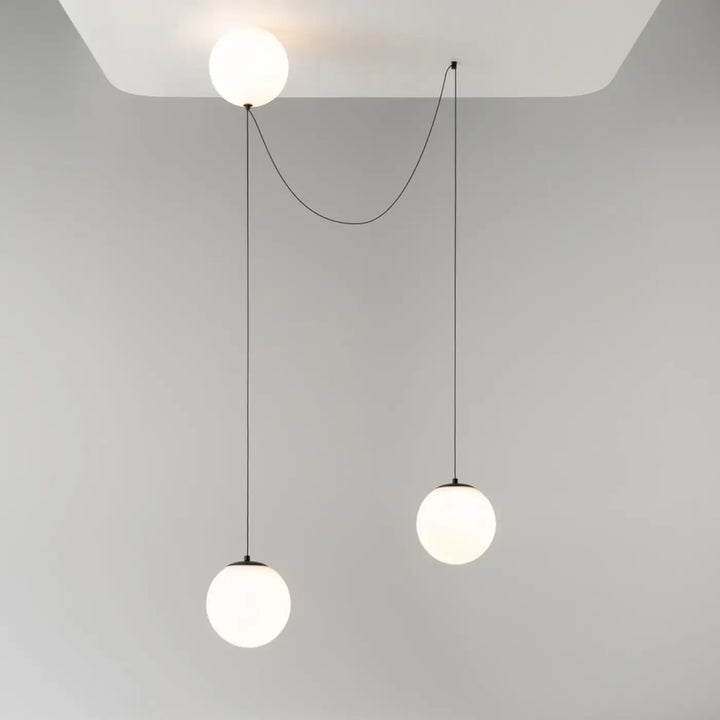 Suspension luminaire twins avec trois globes en verre dépoli suspendus par cordons noirs au-dessus d’une table led