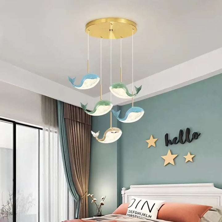 Suspension luminaire aquara avec cinq lampes baleine bleues et vertes suspendues à une base circulaire dorée