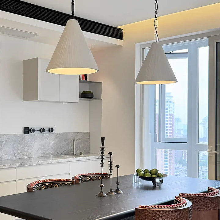 Suspension luminaire halia avec deux luminaires coniques en tissu écru suspendus par chaînes noires au-dessus d’une table noire