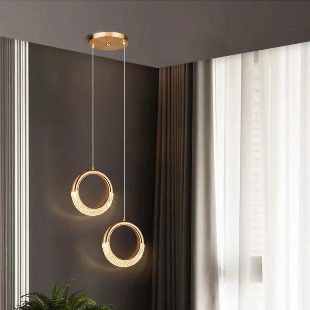 Deux suspensions luminaires décoratives dorées circulaires avec surface texturée et détaillée suspendues au plafond