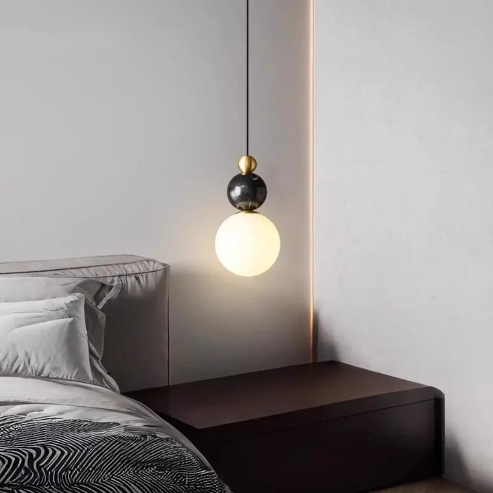 Suspension luminaire eluna avec sphère en marbre noir, accent doré et globe en verre dépoli pour un design moderne