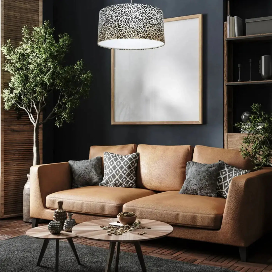 Suspension luminaire design léopard crème avec canapé en cuir tan et coussins à motifs gris et blanc
