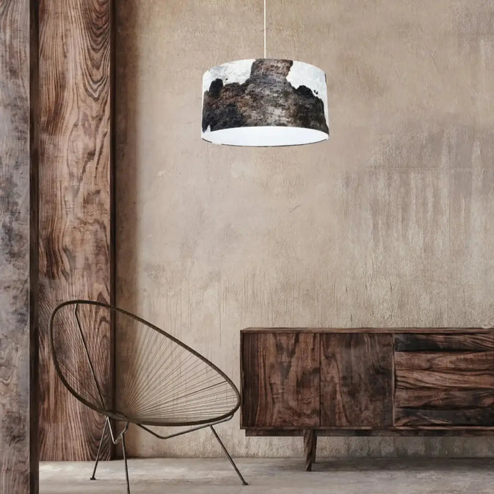 Suspension luminaire marron blanc cylindrique avec intérieur blanc et motif peau de vache noir et blanc suspendu par cordon fin