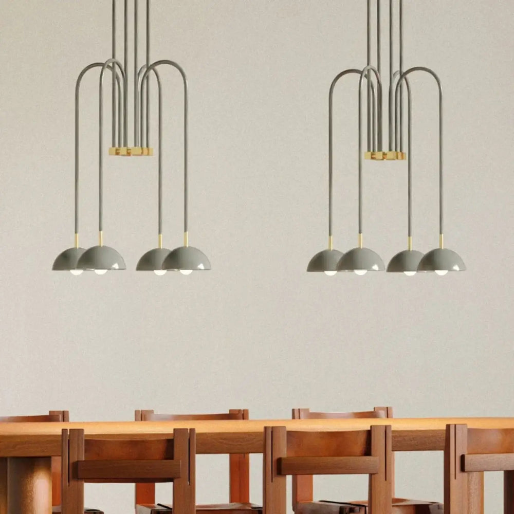 Suspension luminaire rumia gris moderne avec bras incurvés en métal et accents dorés au-dessus d’une table en bois