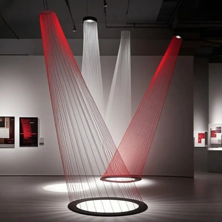Suspension luminaire aloka en rouge et blanc avec jeu d’ombres et design en v formé par des matériaux translucides suspendus