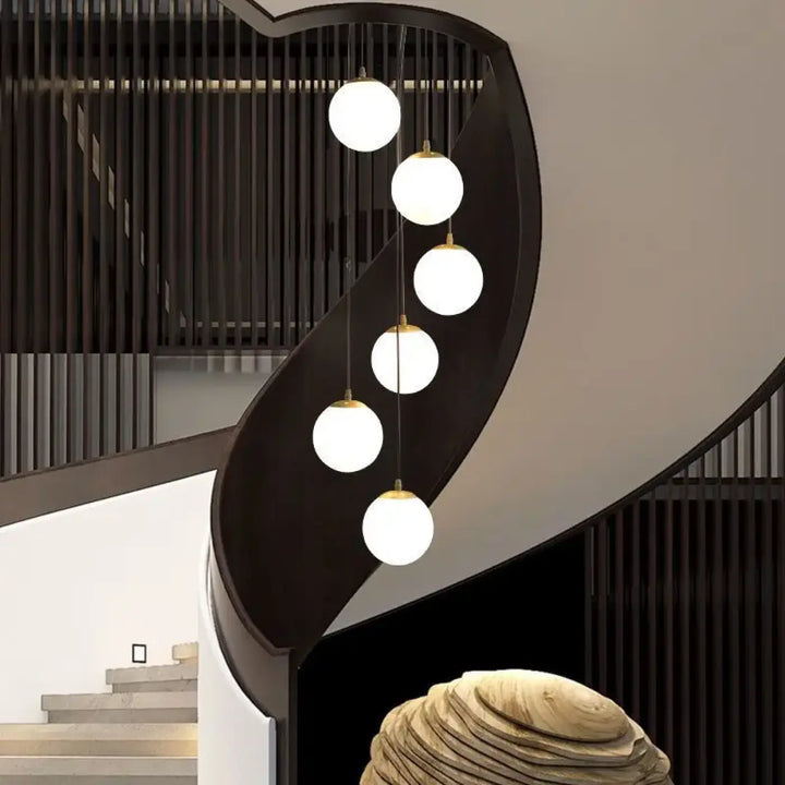 Suspension luminaire umami moderne minimaliste avec cinq globes en verre blanc suspendus par des fixations métalliques dorées