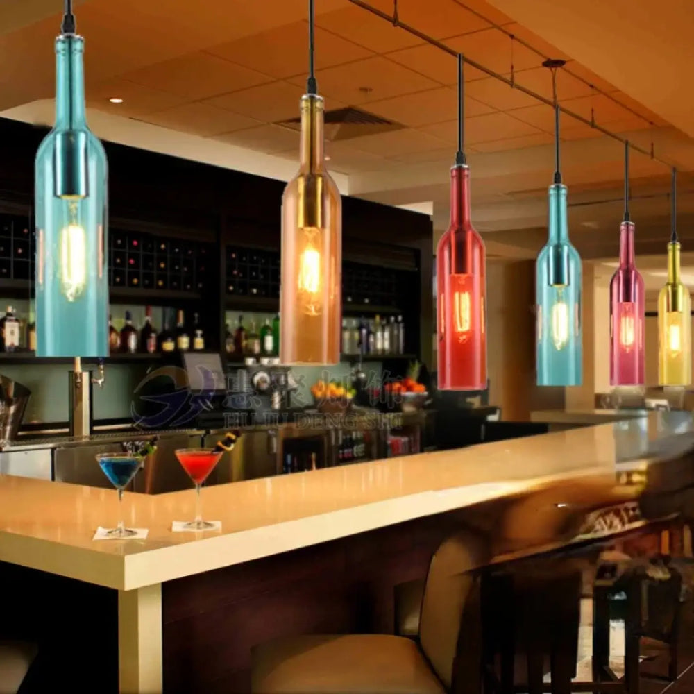 Suspension luminaire aria avec bouteilles colorées en verre suspendues au-dessus d’un comptoir de bar