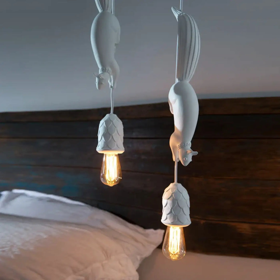 Suspension luminaire forme d’écureuil en céramique blanche avec base pomme de pin texturée et ampoules à filament apparent pour décoration intérieure