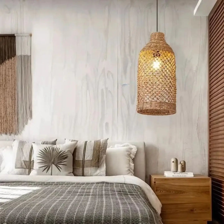 Suspension luminaire mailo en rotin tressé de couleur dorée suspendue au-dessus du lit pour une ambiance nature