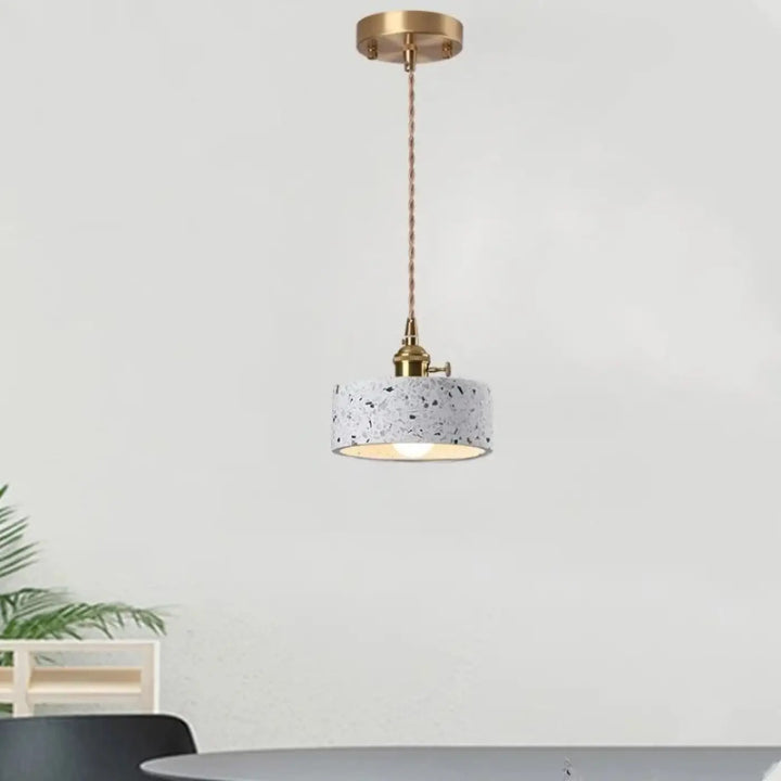 Suspension luminaire tosca avec abat-jour cylindrique en terrazzo et chaîne cordon réglable en finition laiton