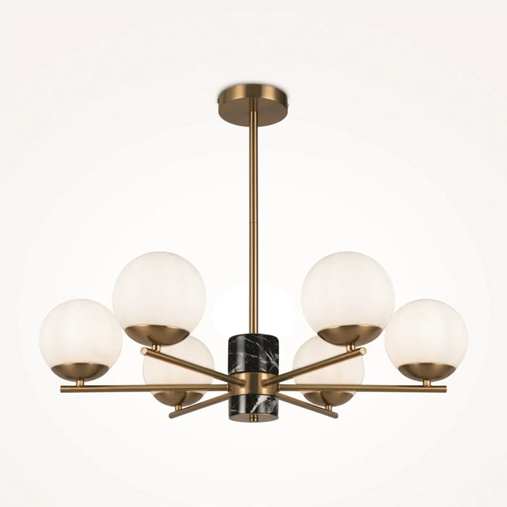 Suspension luminaire marble avec structure dorée, six globes en verre dépoli et accent central en marbre noir au-dessus d’une pièce
