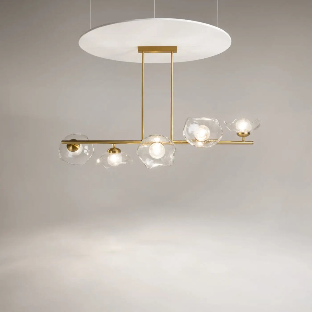 Suspension luminaire miracle avec barre dorée et cinq diffuseurs en verre fleur clair autour d’un diffuseur circulaire blanc