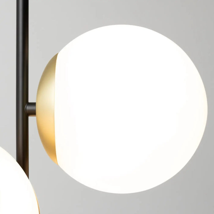 Suspension luminaire trois globes avec globe en verre opalin blanc et acier noir sur tige élégante dorée