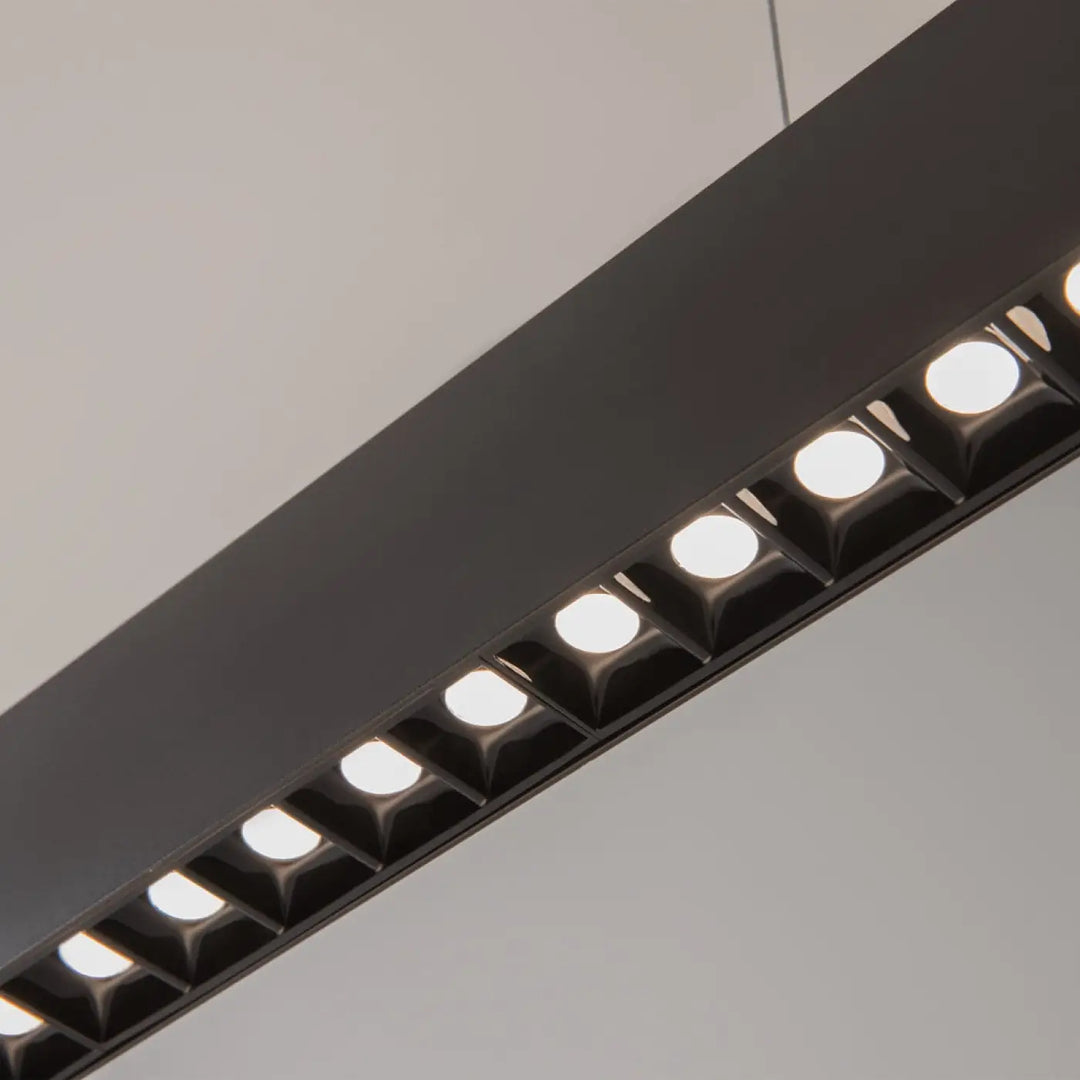 Suspension luminaire points avec barre noire et points lumineux circulaires au-dessus d’un îlot design moderne