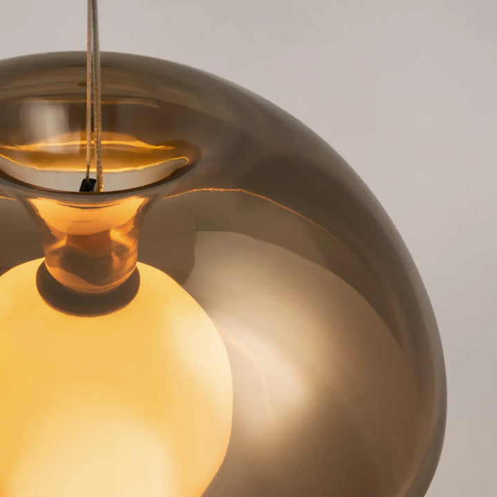 Suspension rebel en verre ambré au design moderne et courbé avec une lumière chaude au-dessus d’une table