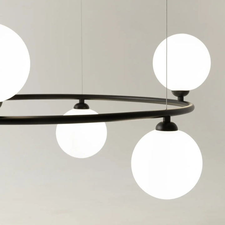 Suspension ring en métal noir moderne avec quatre globes en verre blanc éclairés touche art déco