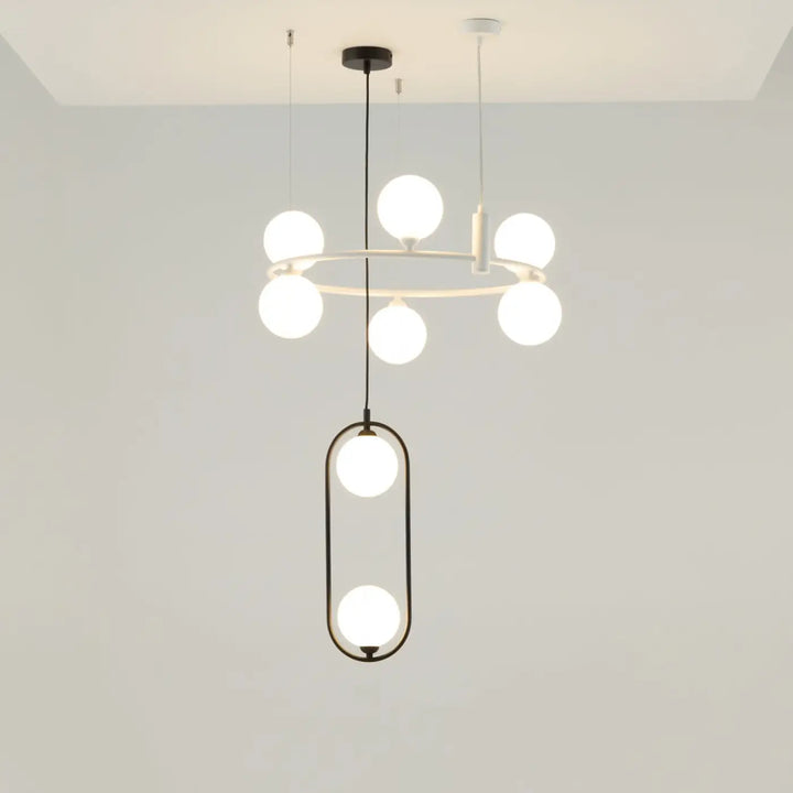 Suspension ring minimaliste au-dessus d’un îlot avec anneau circulaire et cadres ovales noirs tenant des globes en verre dépoli art déco