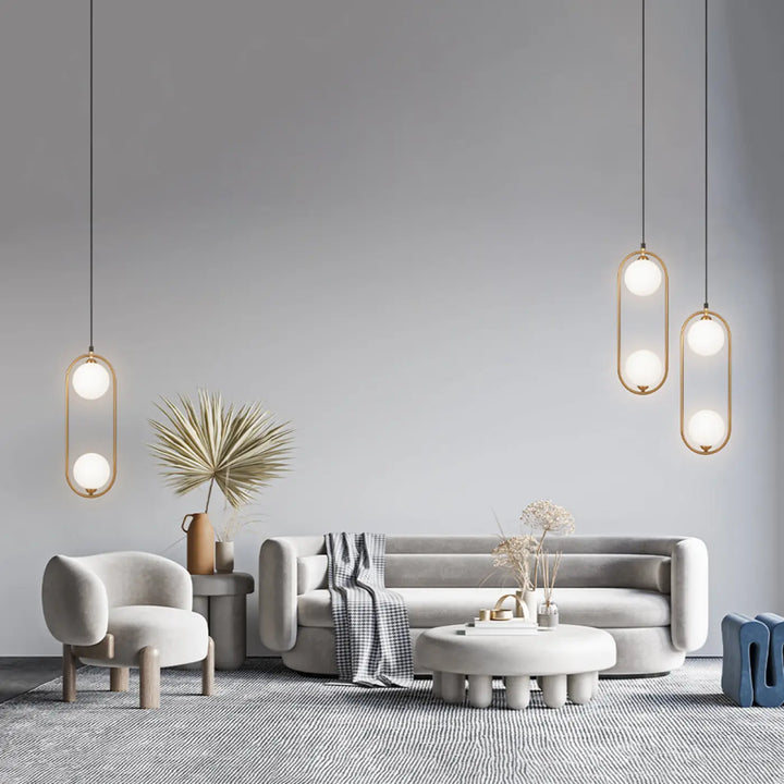 Suspension ring modern minimaliste avec cadres ovales dorés et ampoules en verre dépoli au-dessus d’un îlot art déco