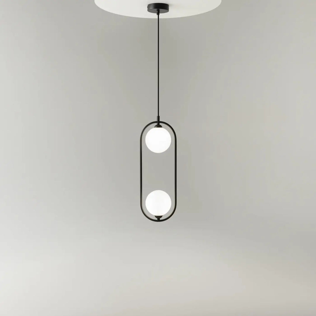 Suspension ring lumineux en métal noir avec deux globes en verre dépoli dans un cadre ovale art déco au-dessus d’un îlot